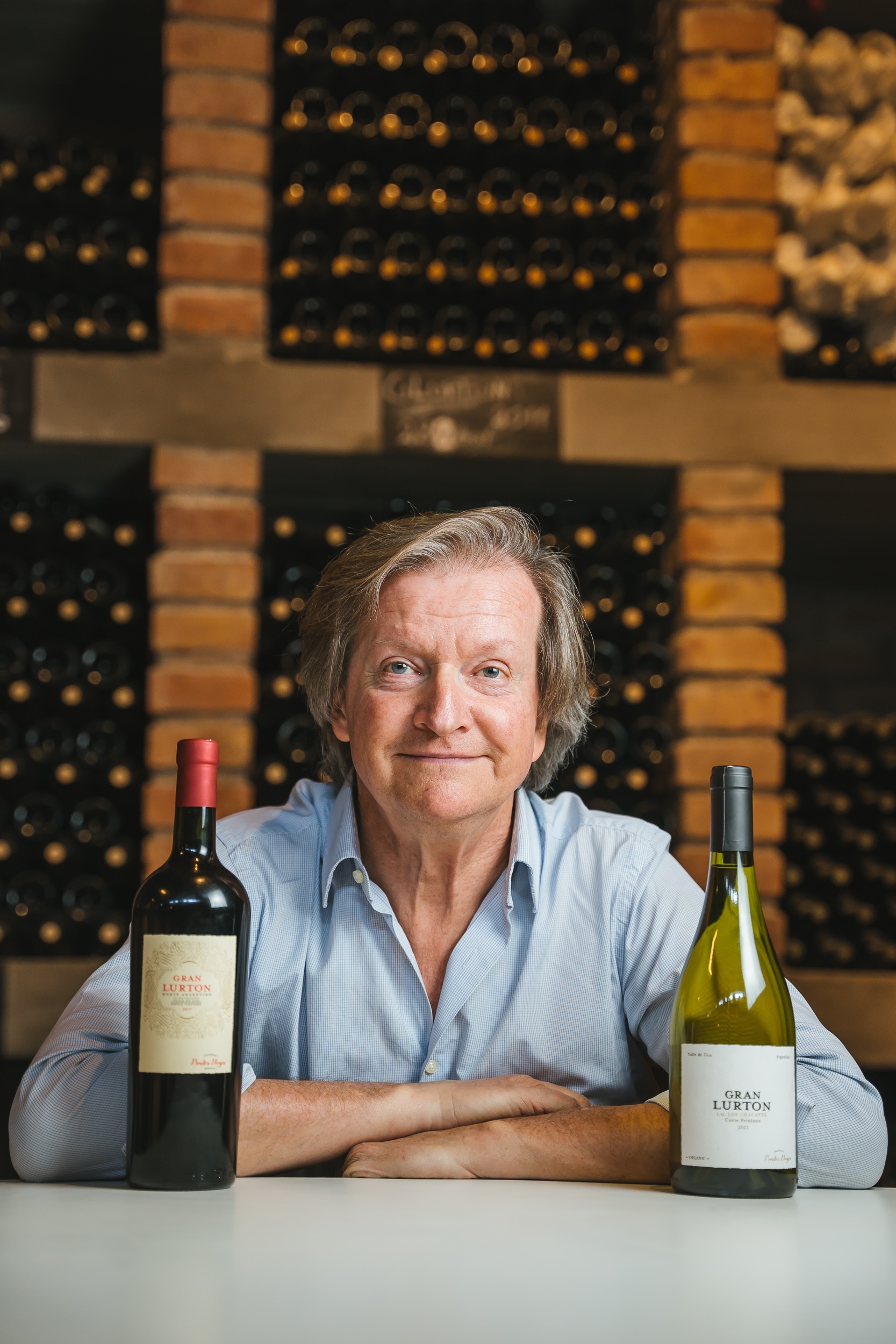 François Lurton, French winemaker and entrepreneur, surrounded by his wines in a wine cellar, reflecting his expertise and passion for winemaking.