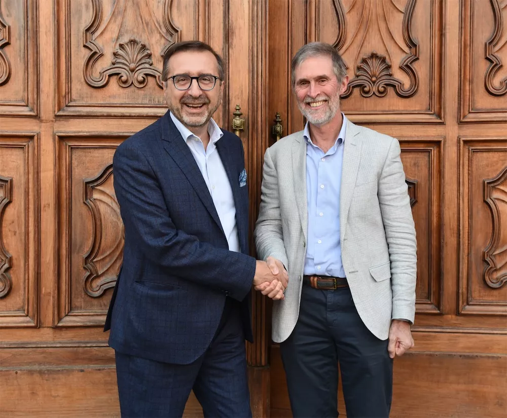 Roberto Bava and Bruno Malavasi, president of the Consorzio del Vermouth di Torino, shaking hands by a carved door