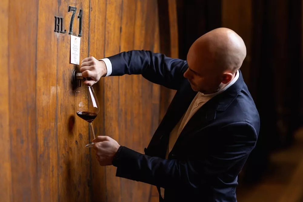 Edoardo Mottini Jacorossi, CEO of Talosa, drawing wine from a large wooden cask into a glass