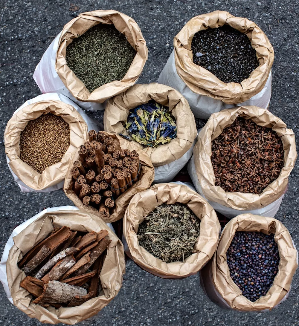 Paper sacks filled with botanicals: bark, cinnamon sticks, dried herbs, seeds and berries